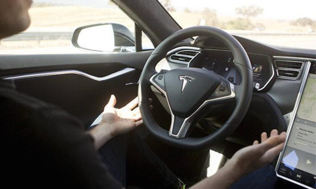 En man kör en Tesla Model S och använder en surfplatta i instrumentbrädan. (AI text)