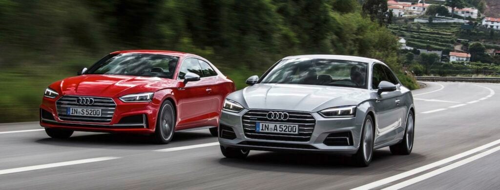 Två Audi A3 kör nedför en landsväg. (AI text)