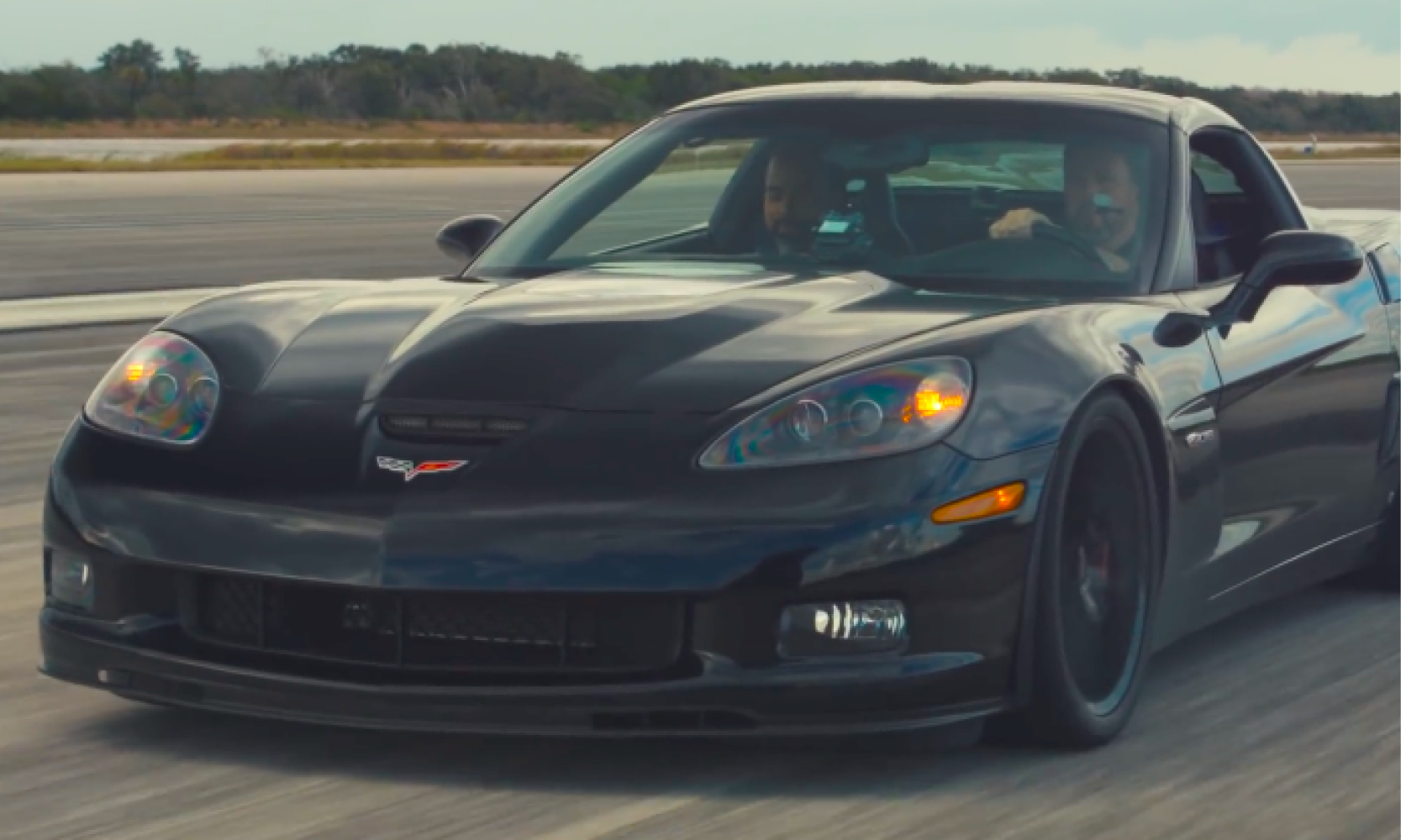 En svart Chevrolet Corvette Z06 kör längs en start- och landningsbana. (AI text)