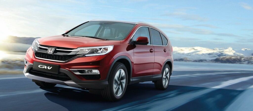 En röd Honda CR-V kör nerför en snöig väg. (AI text)