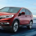 En röd Honda CR-V kör nerför en snöig väg. (AI text)