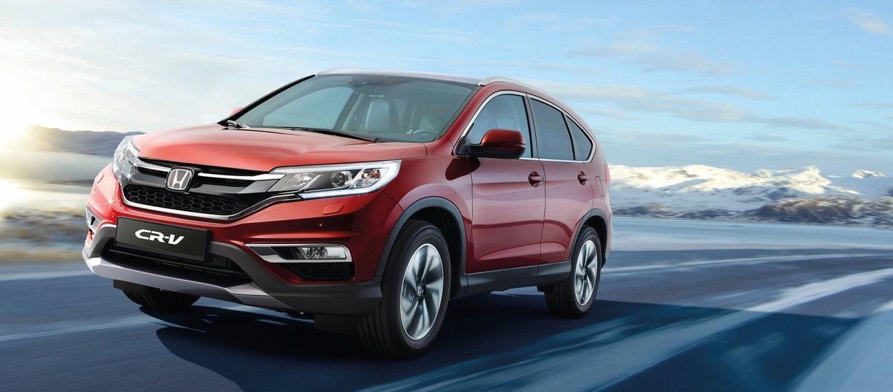 En röd Honda CR-V kör nerför en snöig väg. (AI text)