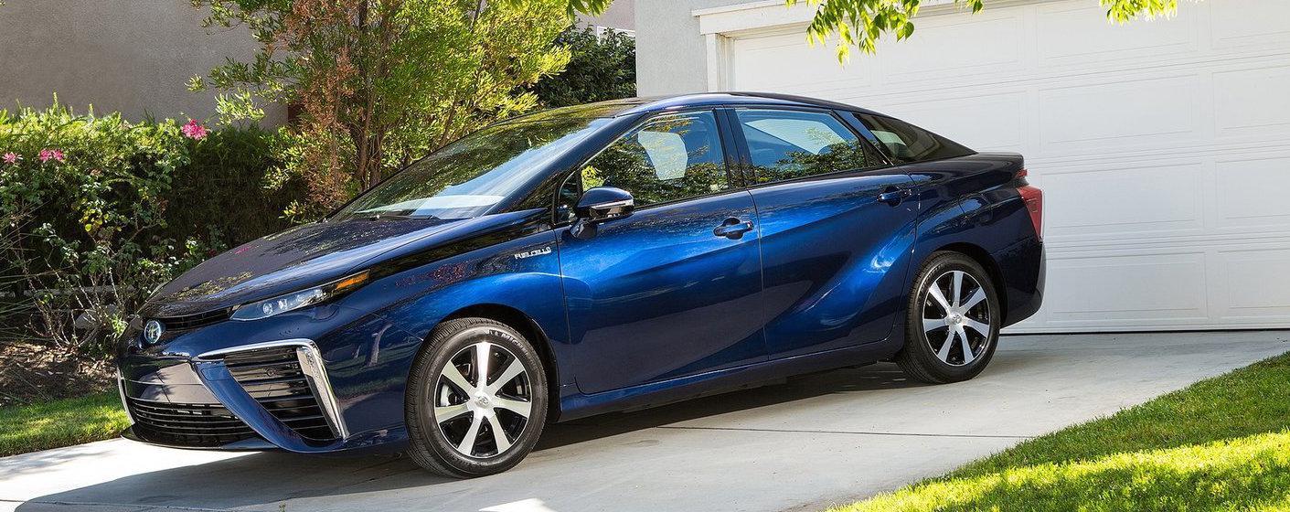 En blå Toyota Prius parkerad framför ett hus. (AI text)