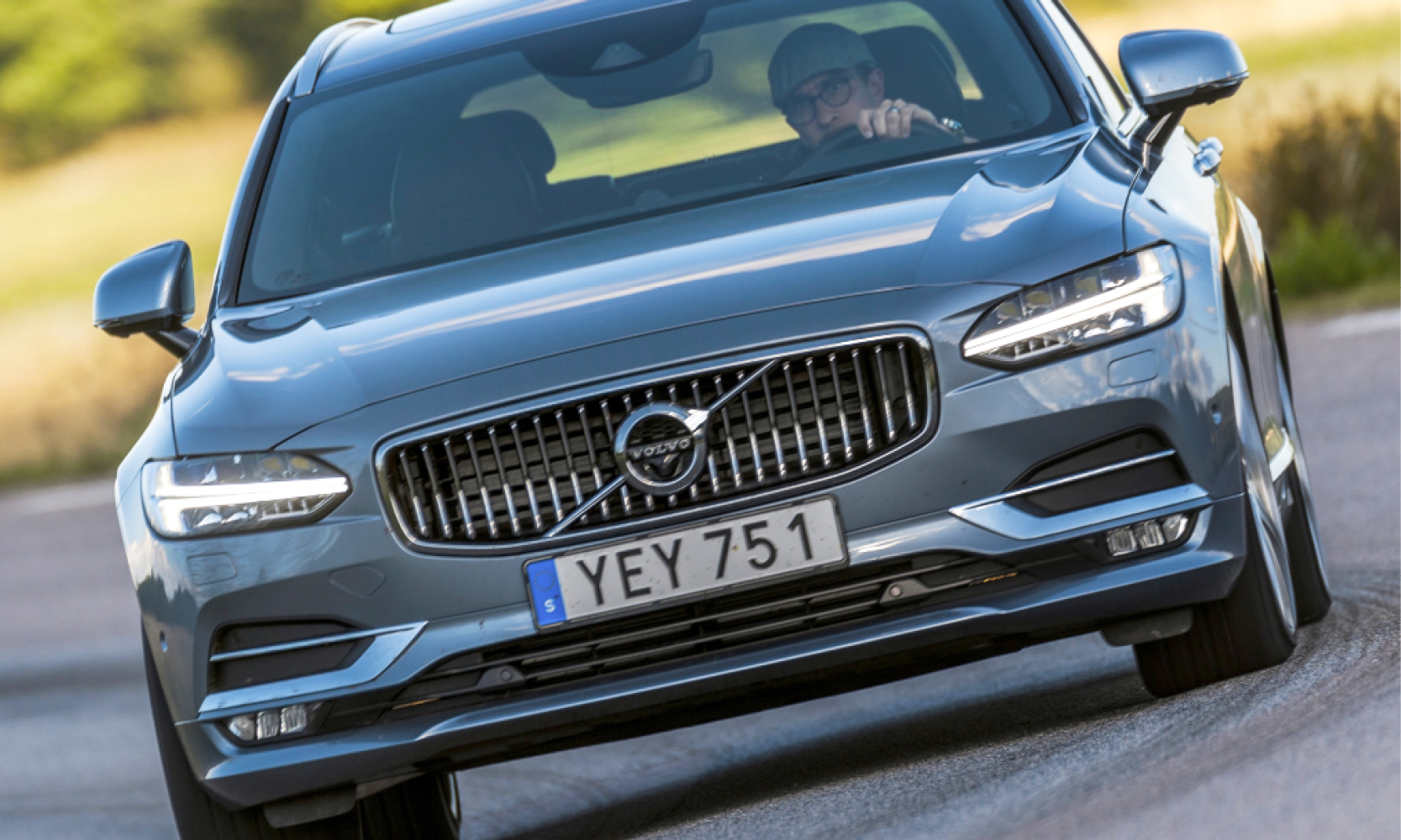 Volvo V90 XDrive SUV kör ner en landsväg. (AI text)