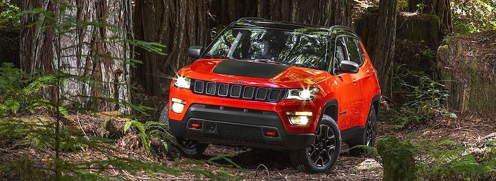 En Jeep Compass kör genom ett skogsbryn. (AI text)