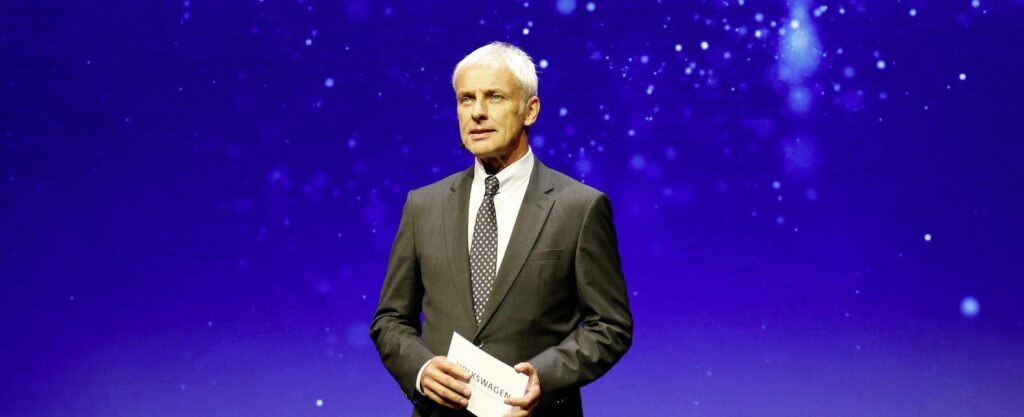 En man i kostym står på scenen. (AI text)