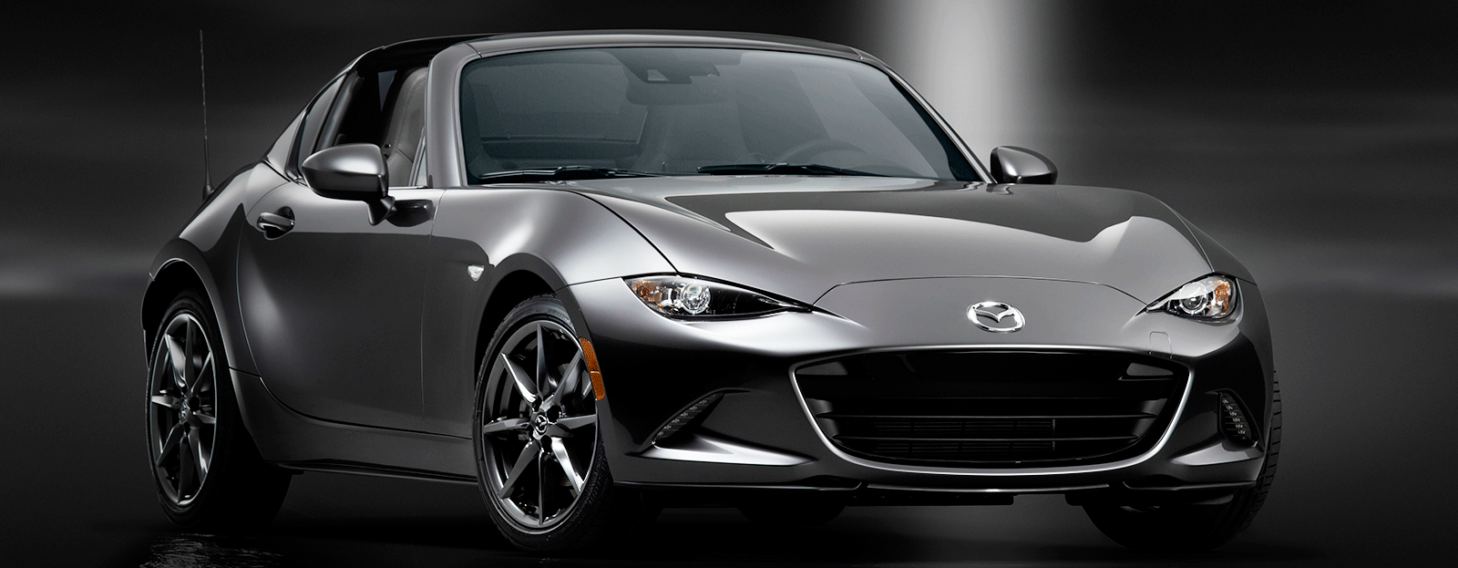 Mazda MX5 Miata står parkerad i en parkeringsplats. (AI text)
