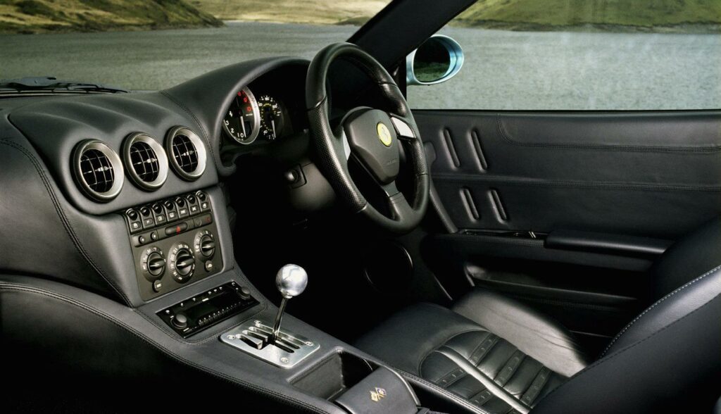 En svart sportbil med läderinredning och utsikt över sjön. (AI text)