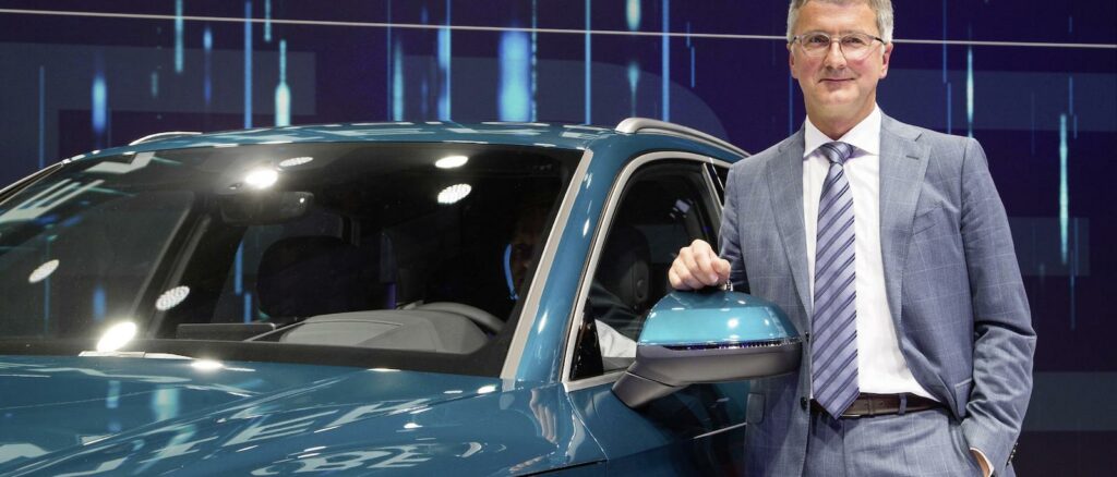 En man i kostym står bredvid en bil. (AI text)