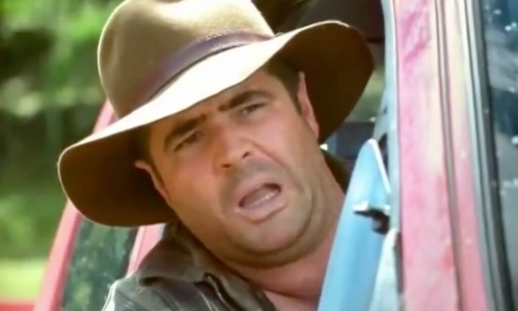 En man i hatt kör en bil. (AI text)