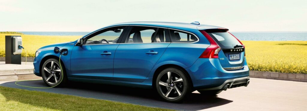 En blå Volvo V40 laddar på en gräsmatta. (AI text)