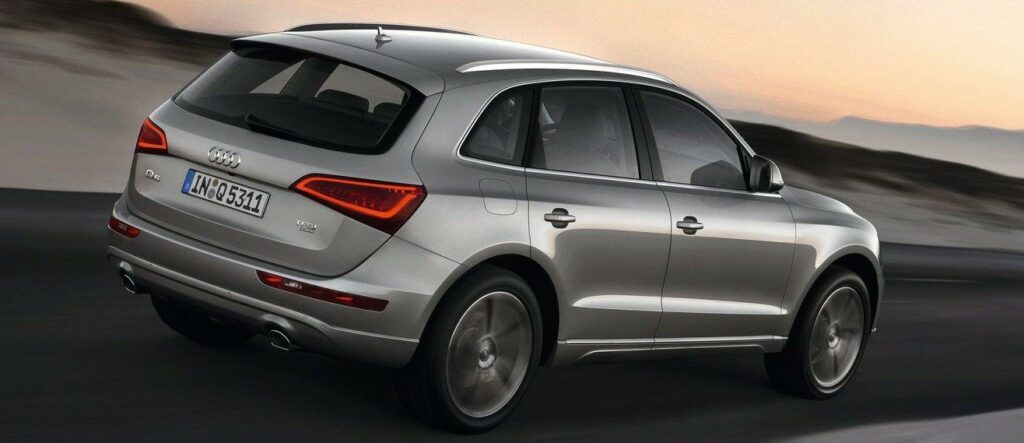 En Audi Q7 SUV kör på en väg under solnedgången. (AI text)