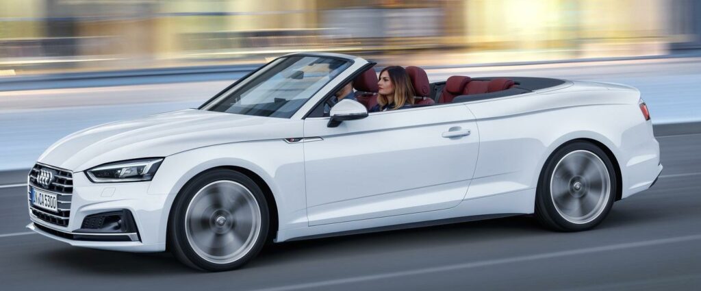 En Audi A5 cabriolet kör på en stadsgata. (AI text)