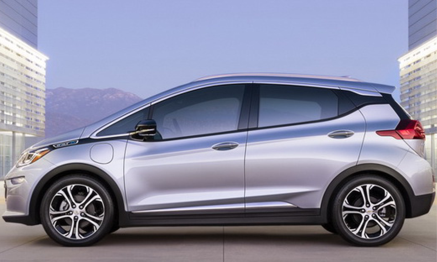 En silverfärgad Chevrolet Bolt parkerad framför ett byggnad. (AI text)