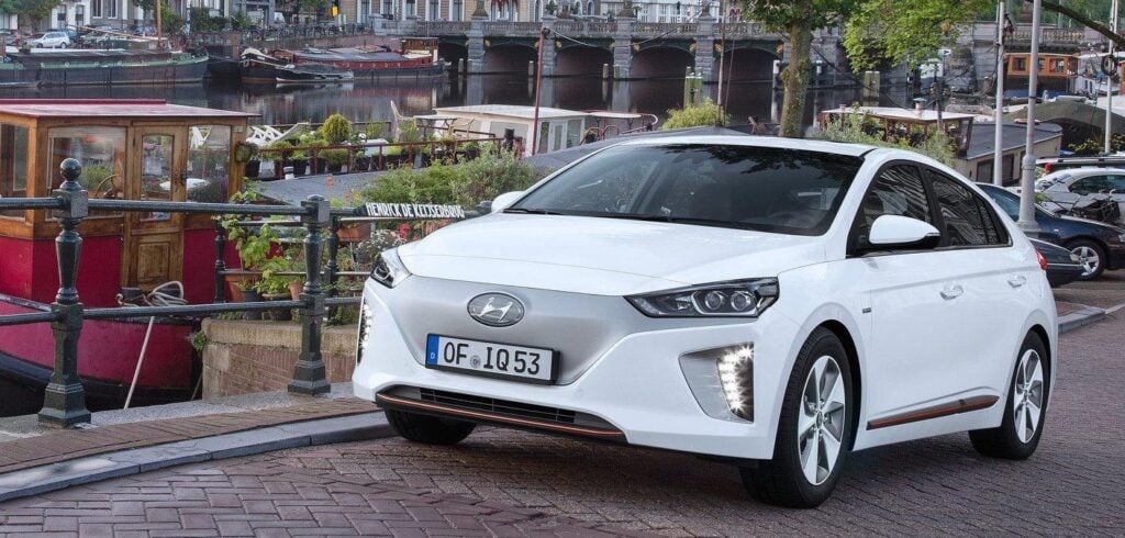 En vit Hyundai Ioniq parkerad på en gata framför ett byggnad. (AI text)