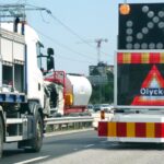 En lastbil kör nedför en motorväg med trafikljus. (AI text)