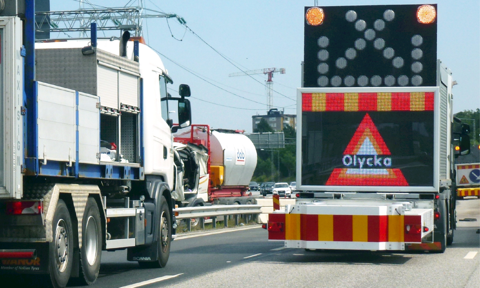 En lastbil kör nedför en motorväg med trafikljus. (AI text)