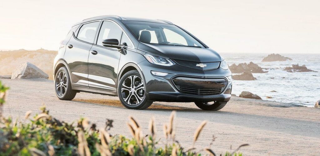 En Chevrolet Bolt EV kör längs en strandväg. (AI text)