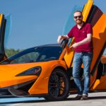 En man står bredvid en McLaren. (AI text)