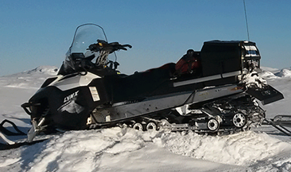 En snöskoter ligger stilla på en snöig backe. (AI text)