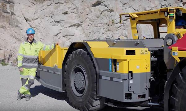 En person står bredvid en stor byggnadsmaskin. (AI text)