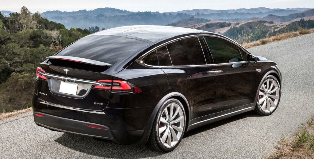 En Tesla Model X kör nerför en bergsväg. (AI text)