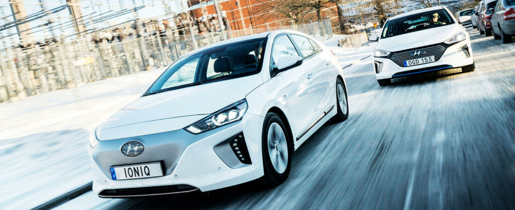 En vit bil kör nedför en snöig gata. (AI text)