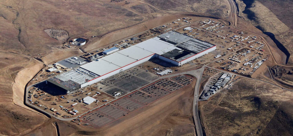 En drönare flyger över byggarbetsplatsen för Teslas fabrik i öknen. (AI text)