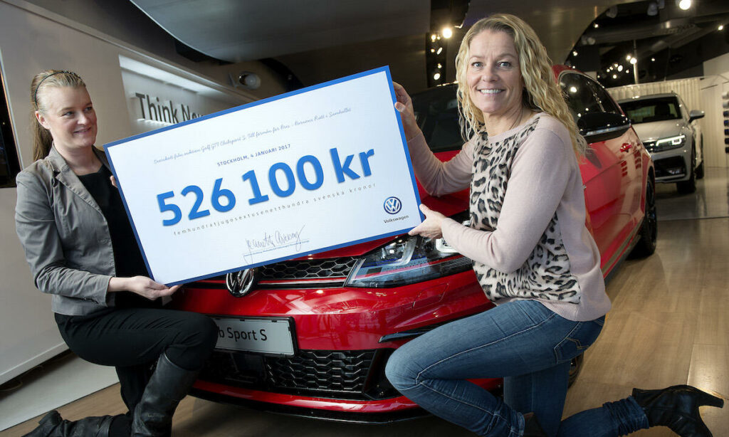 Två kvinnor poserar bredvid en bil i en showrum. (AI text)