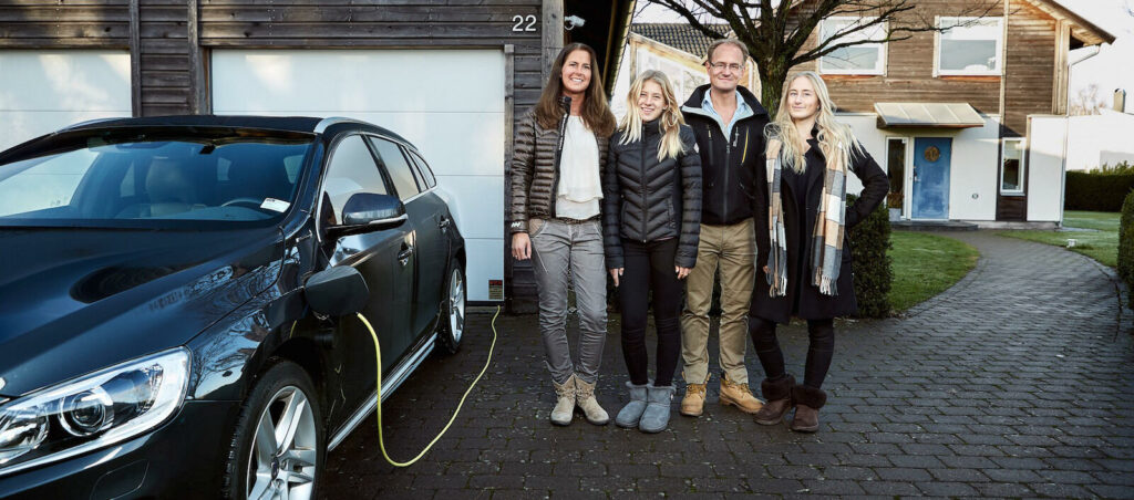 En familj poserar tillsammans med sin bil framför sitt hem. (AI text)