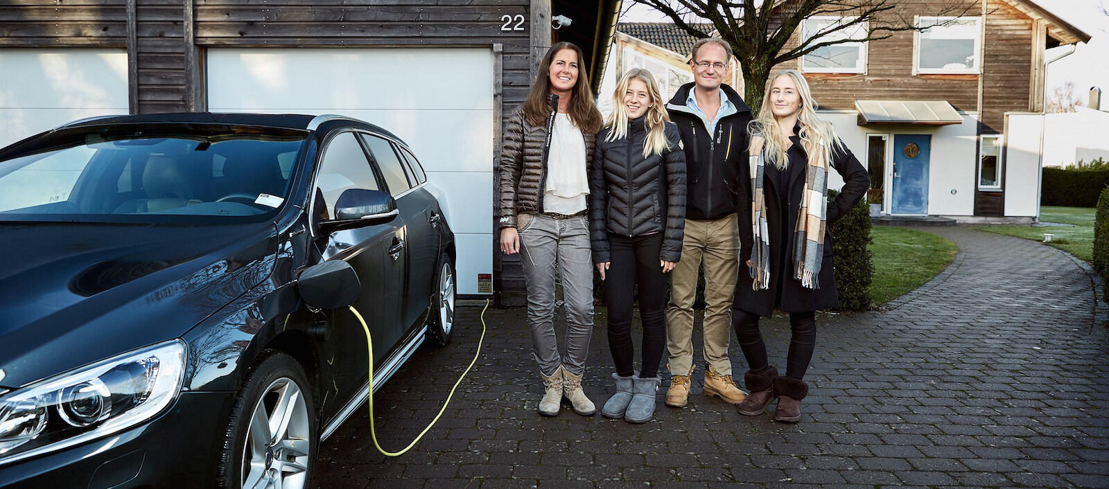 En familj poserar tillsammans med sin bil framför sitt hem. (AI text)