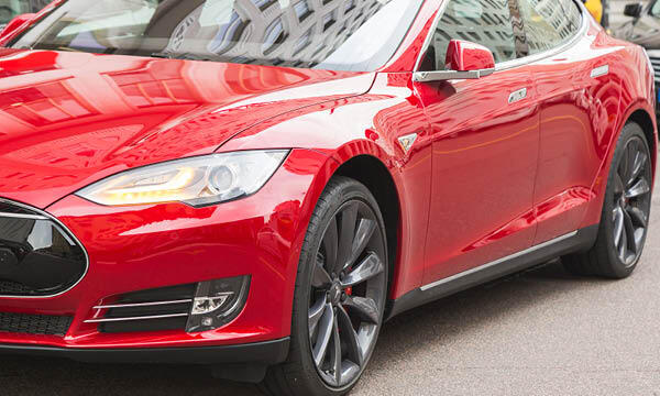 En röd Tesla Model S parkerad på gatan. (AI text)