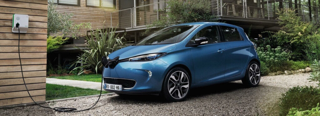 En blå elbil parkerad framför en villa. (AI text)