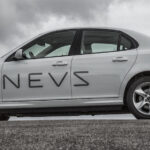 En bil parkerad på en backe med moln i bakgrunden. (AI text)