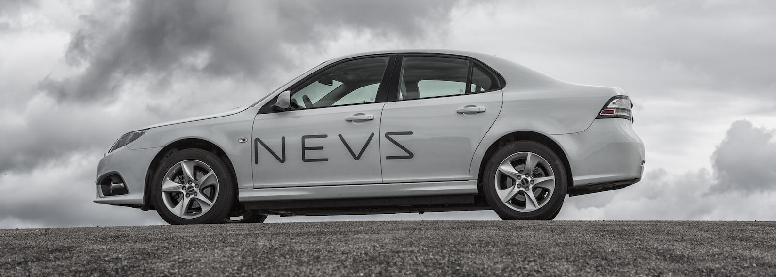 En bil parkerad på en backe med moln i bakgrunden. (AI text)