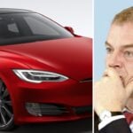 En man i kostym och slips tittar på en Tesla Model S-bil. (AI text)