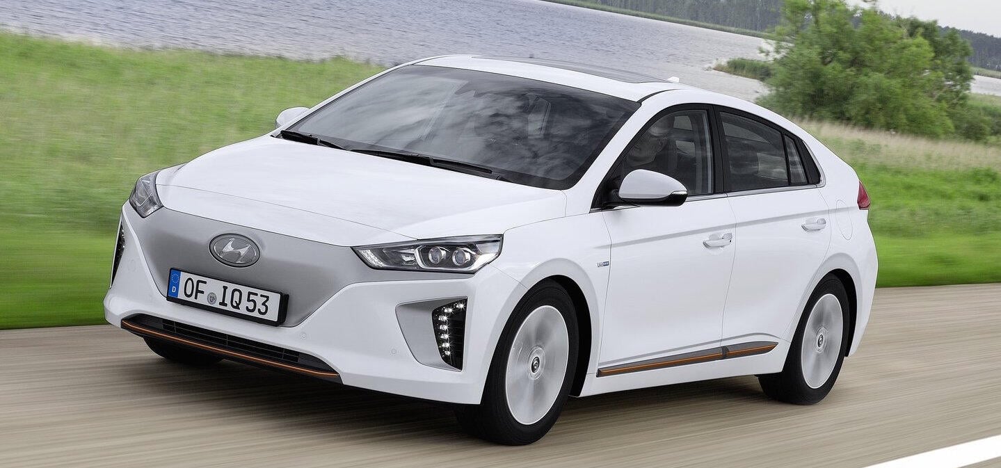 En vit bil körer längs en landsväg. (AI text)