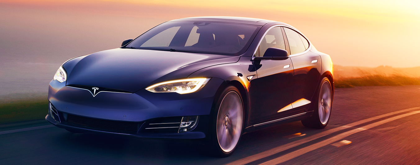 En Tesla Model S kör på en landsväg under solnedgången. (AI text)