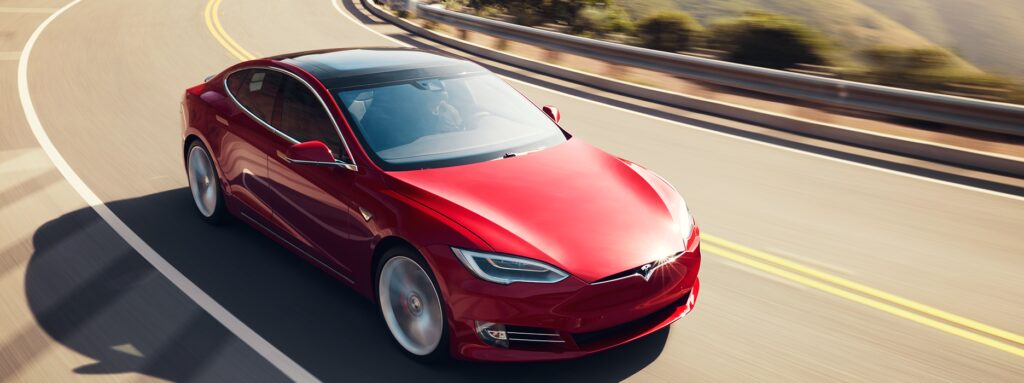En Tesla Model S kör nedför en bergväg. (AI text)