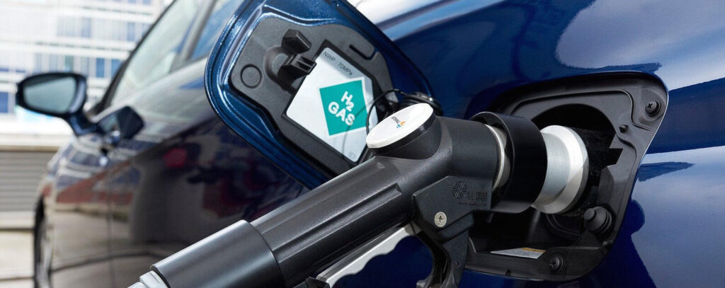 En blå bil står parkerad vid en bensinstation. (AI text)