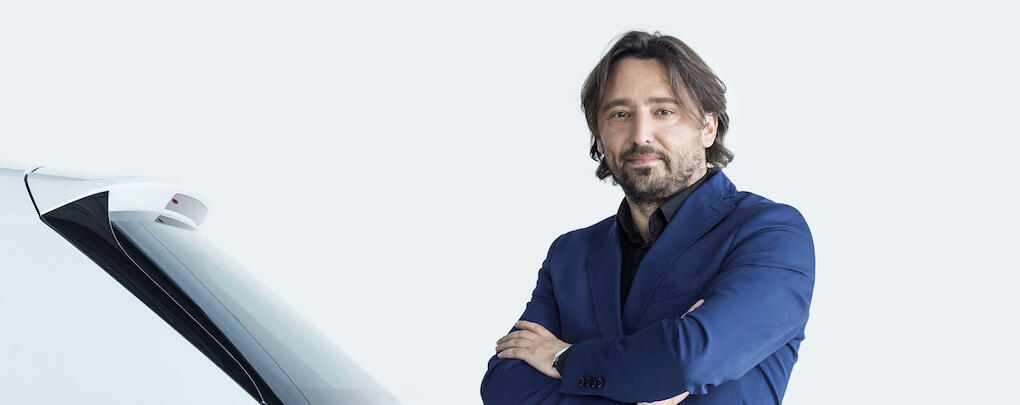 En man i kostym står bredvid en vit bil. (AI text)