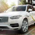 En vit Volvo XC90 kopplad till en elektrisk laddare. (AI text)