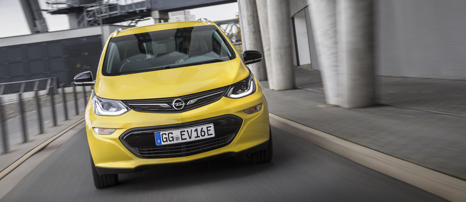 En gul bil körer nerför en gata. (AI text)