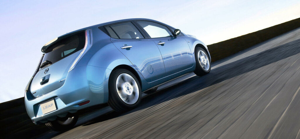 En blå Nissan Leaf kör längs en väg. (AI text)