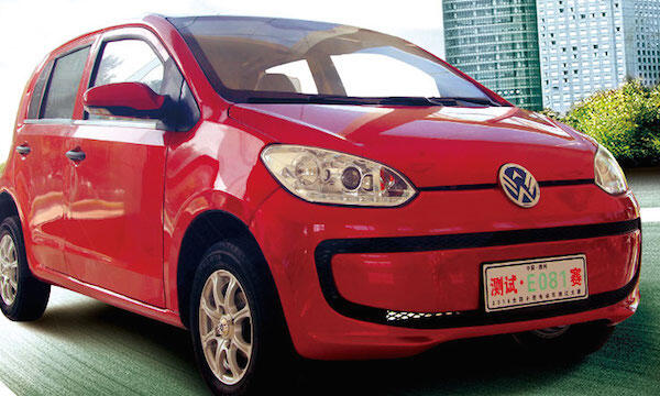 En röd Volkswagen up! körs nedför gatan. (AI text)