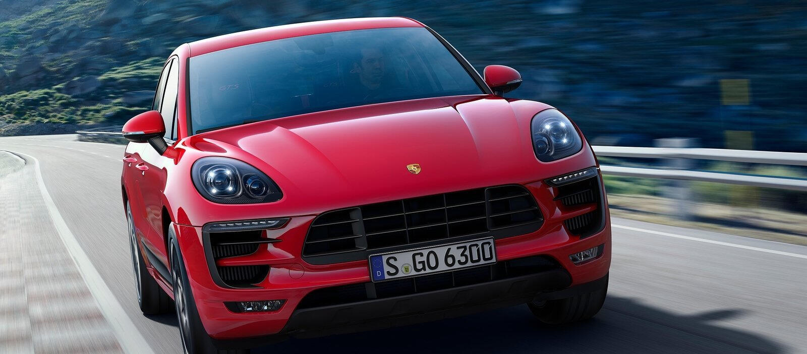 En röd Porsche Macan kör nedför en bergsväg. (AI text)