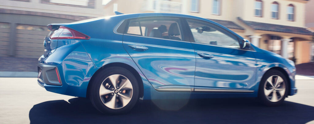 En blå Honda Ilona kör nedför en gata. (AI text)