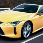 En Lexus LC F-sportbil kör nerför en väg. (AI text)