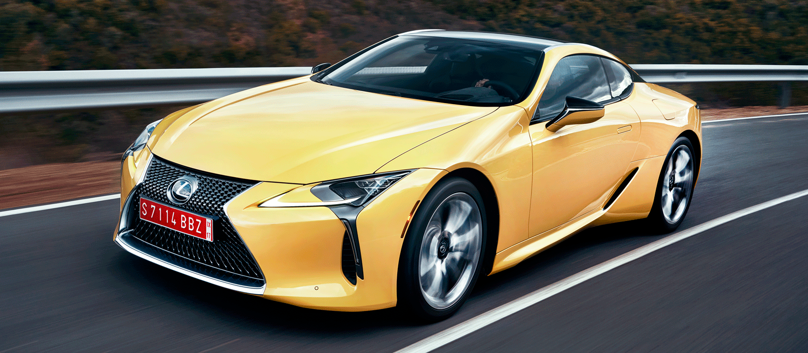 En Lexus LC F-sportbil kör nerför en väg. (AI text)