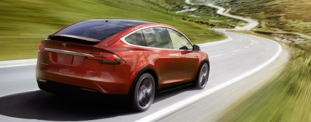 Tesla Model X kör nerför en bergsväg. (AI text)